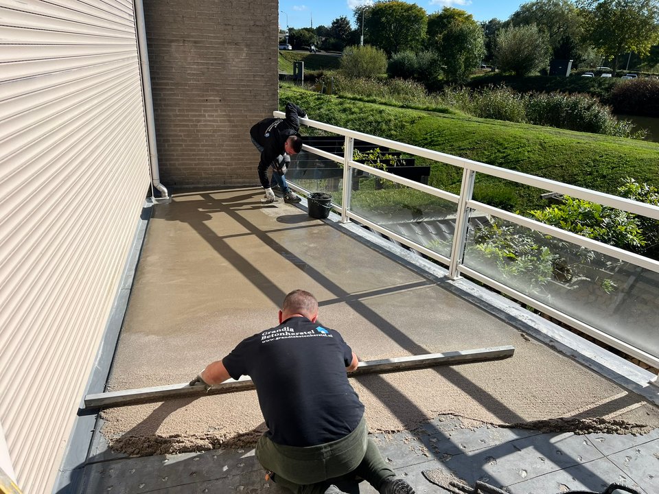 Medewerker werkt de balkonvloer af langs de balustrade