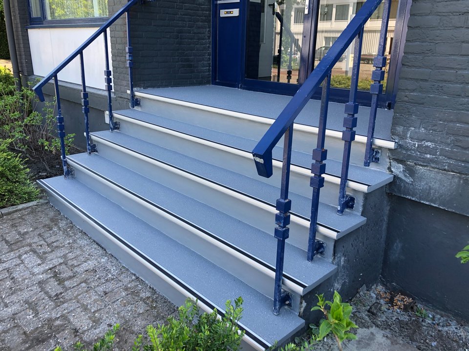 De gerenoveerde entreetrap met antislipneuzen en nieuwe leuning