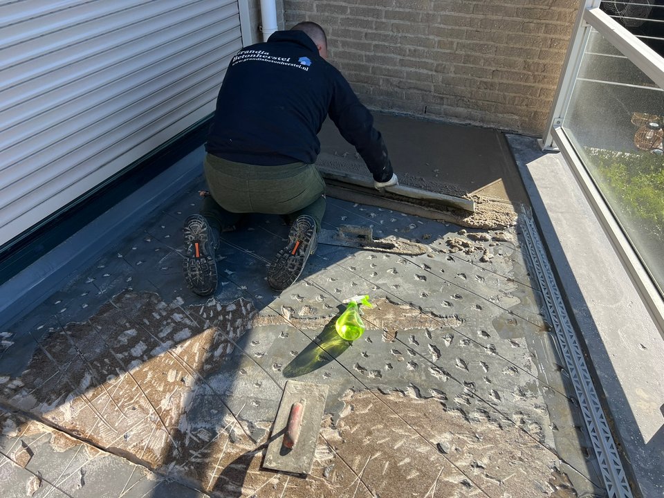 Oude tegelvloer wordt van een balkon verwijderd